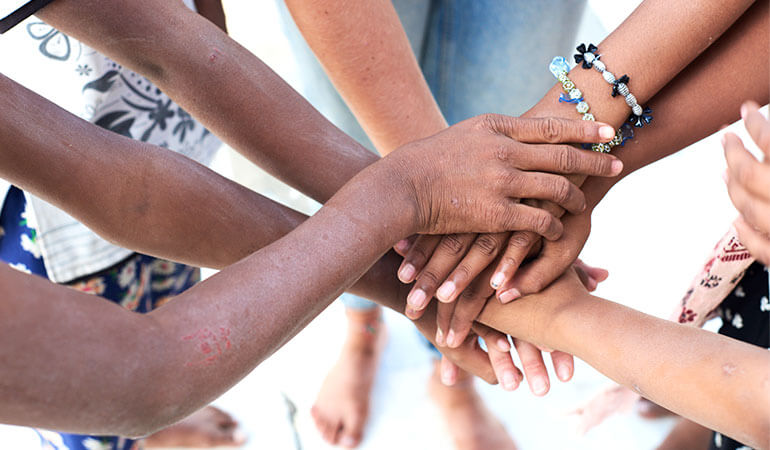 A top view of a group of multiethnic people putting their hands together.