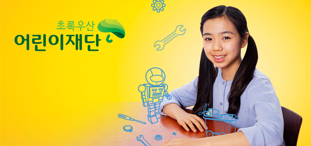 A young girl sitting at a school desk with whimsical illustrations of a robot and tools. This image has a Green Umbrella Children's Foundation logo.